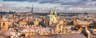 Prague in winter View of skyline in Prague with a light dusting of snow on roofs and sun breaking through dark gray clouds.